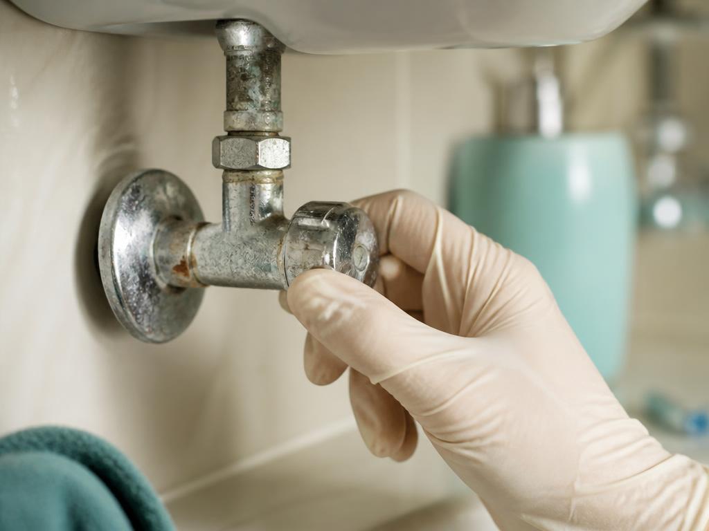 Plumber testing toilet shut-off valve operation during a preventative water leak audit